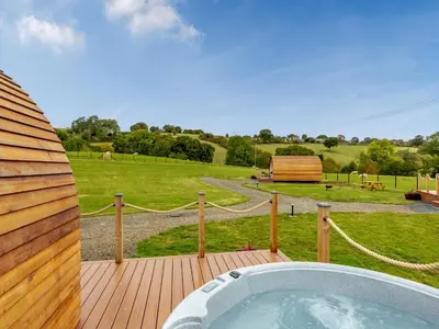 a hot tub on a deck with a view of a field at Elm-Uk36259 in Llanfair Caereinion
