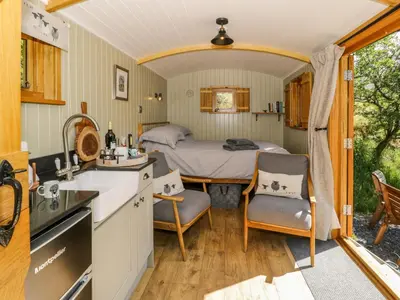 a kitchen and a bedroom with a bed in a room at Moelfre - Shepherds Hut in Llanbedr