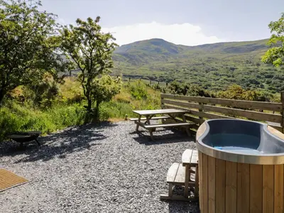 a hot tub and a picnic table with a view at Moelfre - Shepherds Hut in Llanbedr