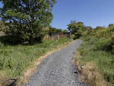 a gravel road in a field with a wooden fence at Moelfre - Shepherds Hut in Llanbedr