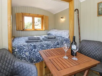a room with a bed and a table with wine glasses at Llethr - Shepherds Hut in Llanbedr