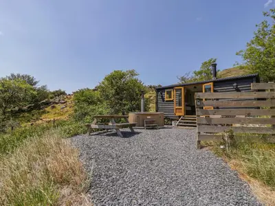 a cabin with a picnic table and a wooden fence at Llethr - Shepherds Hut in Llanbedr