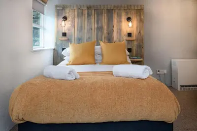 a bedroom with a large bed with two towels on it at Granary Retreat for 2 inc shared Dog Field in Bryn-crug