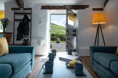 a living room with two blue couches and a window at Cowshed Cottage with Log Burner & Shared Dog Field in Bryn-crug
