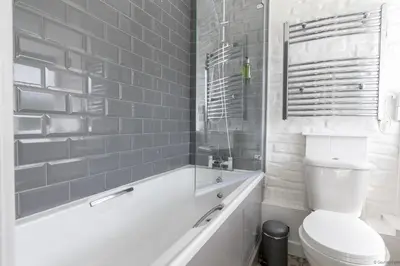 a white bathroom with a toilet and a tub at Cowshed Cottage with Log Burner & Shared Dog Field in Bryn-crug