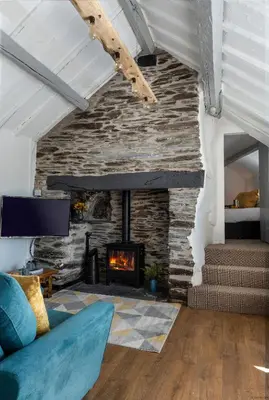 a living room with a stone fireplace and a couch at Cozy Log Burner Cottage & On-Site Dog Field in Bryn-crug