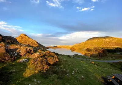 a view of a lake in a field with rocks at Cozy Log Burner Cottage & On-Site Dog Field in Bryn-crug