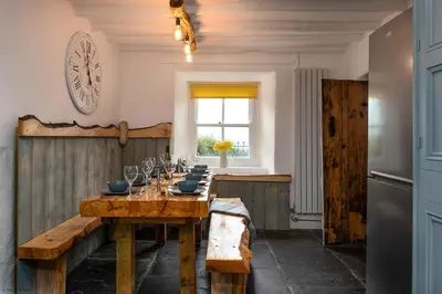a dining room with a table and a clock on the wall at Farmhouse with Log Fire & On-Site Dog Field in Bryn-crug
