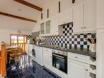 a kitchen with white cabinets and black and white tiles at Robins Nest - Uk36208 in Llanfihangel-y-creuddyn