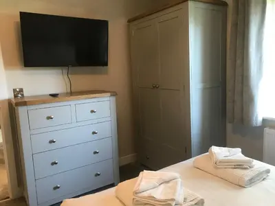 a bedroom with a white dresser and a tv on the wall at Haul y Bore in Aberystwyth