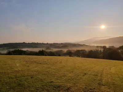a field with the sun rising over a misty field at Ty Twt in Lampeter