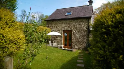 a stone house with a table and chairs in a yard at Ty Twt in Lampeter