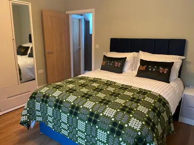 a bedroom with a bed with a green and white comforter at Pennant Uchaf in Llanbrynmair