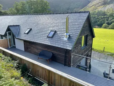 a house with a deck with a chair on it at Pennant Uchaf in Llanbrynmair