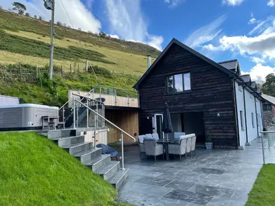 a house with a patio and stairs next to a hill at Pennant Uchaf in Llanbrynmair