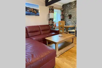 a living room with a leather couch and a table at Hendre Fechan Cottage, Nr Barmouth, Pets welcome, beautiful views. in Llanddwywe