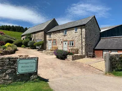 a stone house with a sign in front of it at The Nook at Pentregaer Ucha, with tennis court & lake. in Oswestry