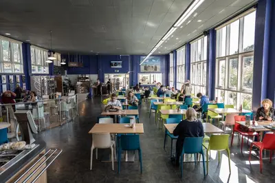a cafeteria with tables and people sitting at tables at Aberystwyth University Bunkhouse in Aberystwyth