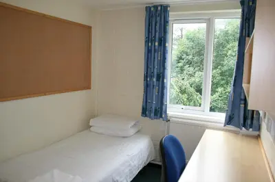a small room with two beds and a window at Aberystwyth University Bunkhouse in Aberystwyth
