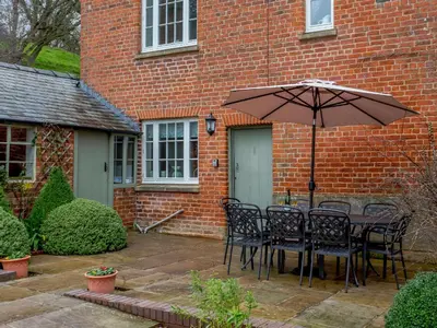 a table and chairs with an umbrella in front of a brick building at Old Upper Gwestydd in Highgate
