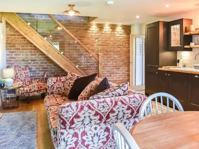 a living room with a couch and a brick wall at Afonig Loyw in Dyffryn