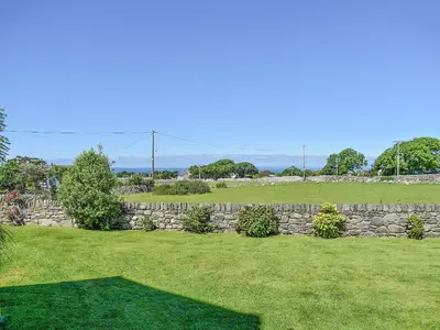 a stone wall in a yard with a green field at Afonig Loyw in Dyffryn