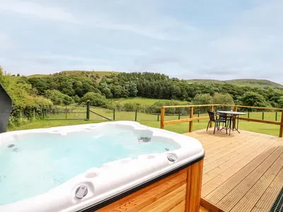 a hot tub on a deck with a table and chairs at Hwyl in Llandrindod Wells