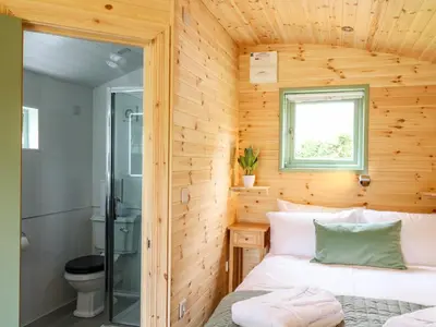 a bedroom with wooden walls and a bed with a window at Hwyl in Llandrindod Wells