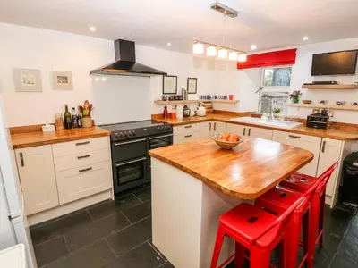 a kitchen with a wooden table and red stools at Gerlan in Harlech
