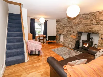 a living room with a stone fireplace and a staircase at Gerlan in Harlech