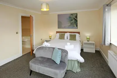 a bedroom with a white bed and a chair at St Julians Place in Shrewsbury