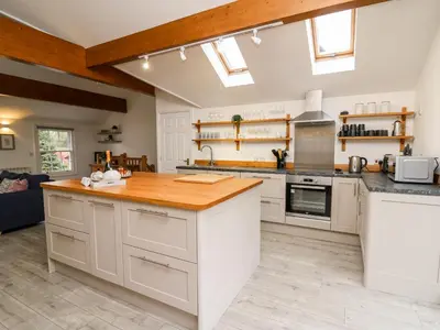 a kitchen with white cabinets and a wooden counter top at Bridgend Cottages in Llandrindod Wells