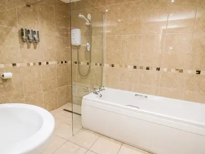 a bathroom with a tub and a toilet and a sink at Bridgend Cottages in Llandrindod Wells
