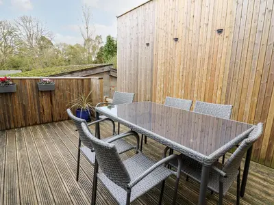a table and chairs on a deck with a fence at Bridgend Cottages in Llandrindod Wells