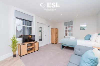 a bedroom with a bed and a tv and a couch at Studio 2, Second Floor Town Centre Apartment in Shrewsbury