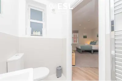 a white bathroom with a bed in a room at Studio 2, Second Floor Town Centre Apartment in Shrewsbury