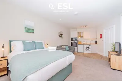 a bedroom with a large bed and a living room at Studio 2, Second Floor Town Centre Apartment in Shrewsbury
