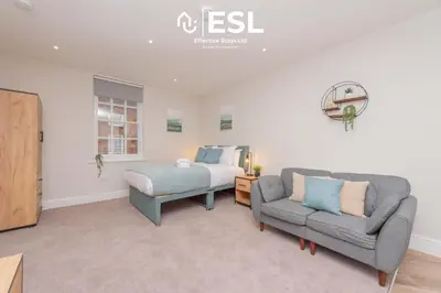 a bedroom with a bed and a couch and a chair at Studio 2, Second Floor Town Centre Apartment in Shrewsbury
