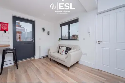 a living room with a chair and a door at Studio 3, Top Floor Town Centre Apartment in Shrewsbury