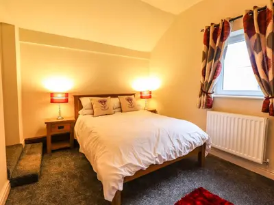 a bedroom with a bed and a window and two lamps at Bodaioch Cottage in Caersws