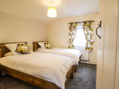 two beds in a room with a window at Bodaioch Cottage in Caersws