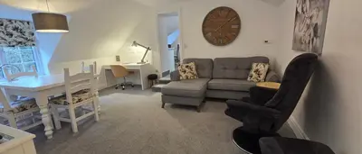 a living room with a couch and a table and a clock at Modern and spacious 2 bedroom apartment with free parking in Glyn-Ceiriog