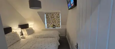 a small bedroom with two beds and a window at Modern and spacious 2 bedroom apartment with free parking in Glyn-Ceiriog