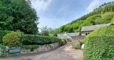 a house with a stone wall and a driveway at Modern and spacious 2 bedroom apartment with free parking in Glyn-Ceiriog