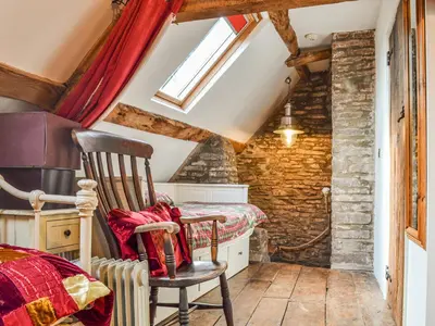 a small attic room with a chair and a bed at Ty Fferm Hen - Uk36420 in Talybont
