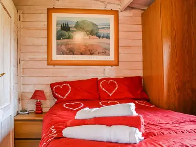 a red bed with heart pillows on it in a room at Ty Bach Twt - Uk36419 in Talybont