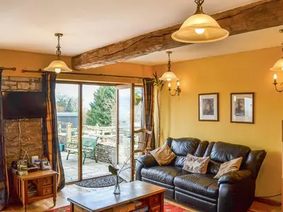 a living room with a leather couch and a table at Peacock Cottage - Uk36422 in Talybont