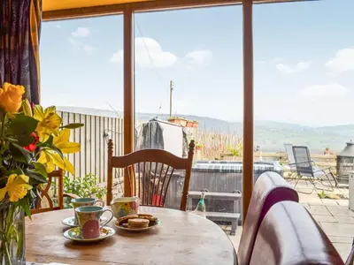 a wooden table with plates of food on a balcony at Peacock Cottage - Uk36422 in Talybont