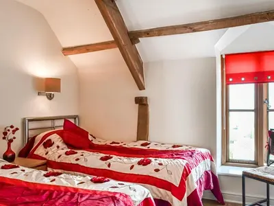 two beds in a room with red and white sheets at Peacock Cottage - Uk36422 in Talybont