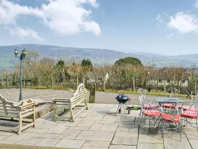 a patio with chairs and a table and a grill at Ty Nofio - Uk36421 in Talybont